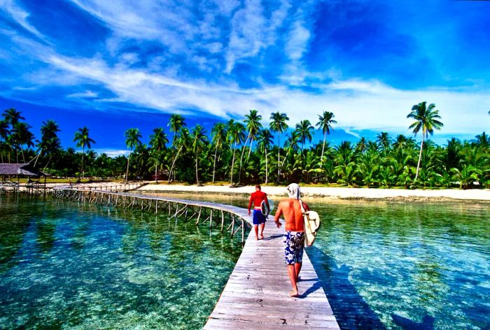 Surfers stroll along a boardwalk on Siargao Island, The Philippines