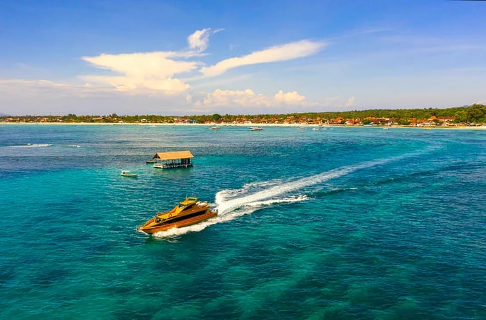 A fast-boat departs from Nusa Lembongan in Bali, Indonesia, leaving a white wake behind.