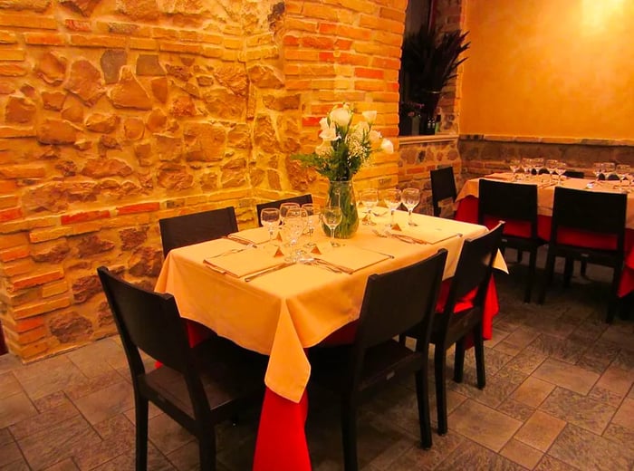 An inviting restaurant interior featuring a dinner table set against a backdrop of exposed brick.