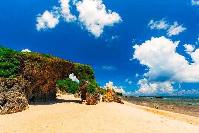 A glimpse of a sandy beach framed by a rock arch on Sabtang Island, Philippines