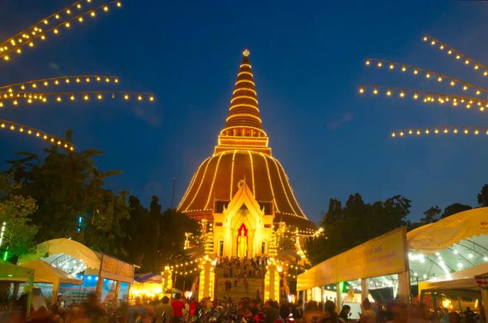 Buddhists gather at Phra Pathom Chedi in Nakhon Pathom during dusk.