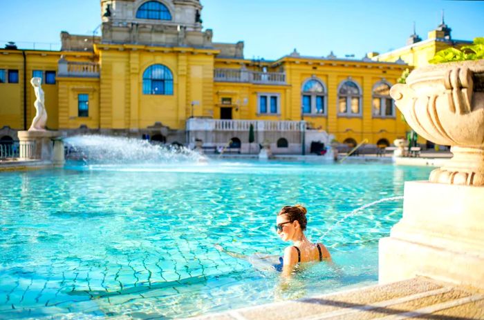 A woman enjoys a sunny outdoor bath at Széchenyi Baths in Budapest