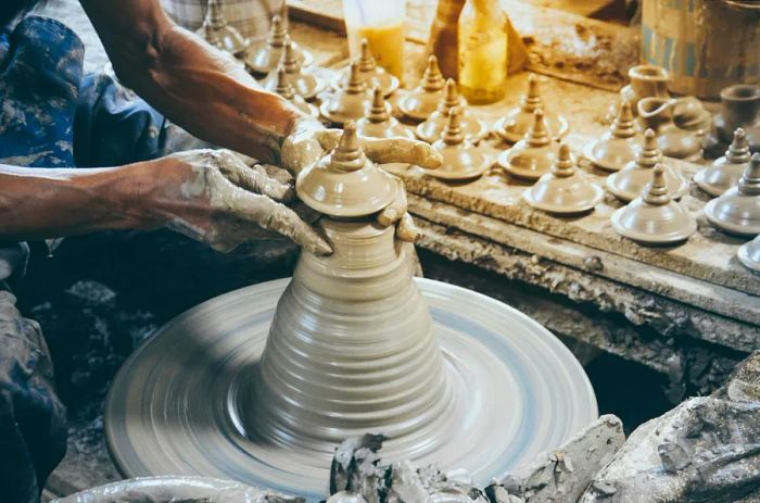 A potter shaping a traditional Thai pot lid on a wheel at Ko Kret; perfect for day trips from Bangkok.