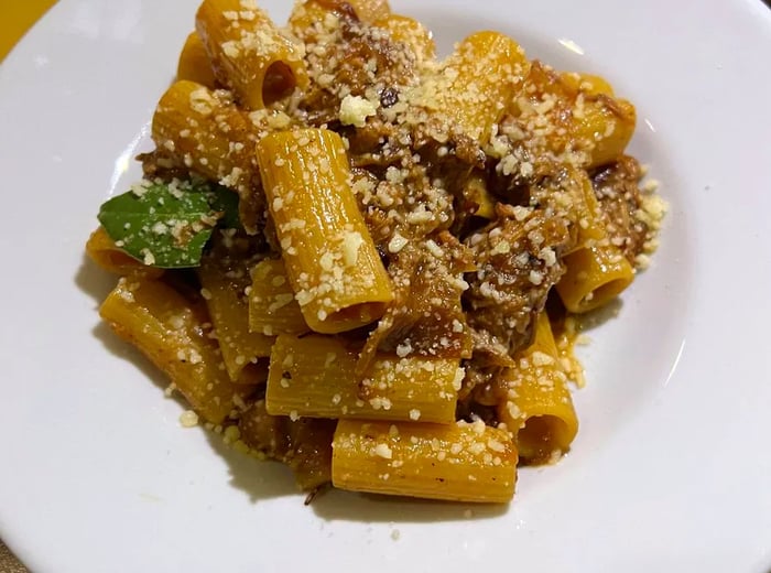 Robust rigatoni pasta topped with beef, grated cheese, and aromatic herbs.