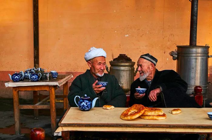 Uzbek men engage in conversation and enjoy tea in a traditional chaikhana (tea house).