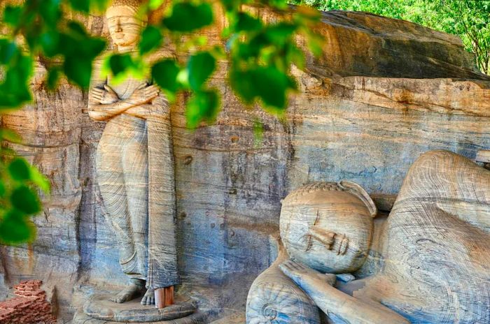 Giant Buddha statues framed by the foliage at the Gal Vihara temple complex, Polonnaruwa, Sri Lanka.