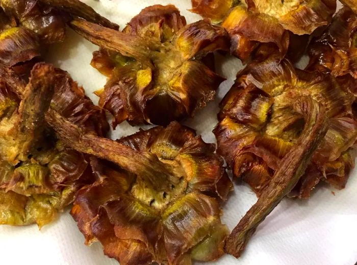 Golden fried artichoke hearts resting on a paper towel-lined tray.