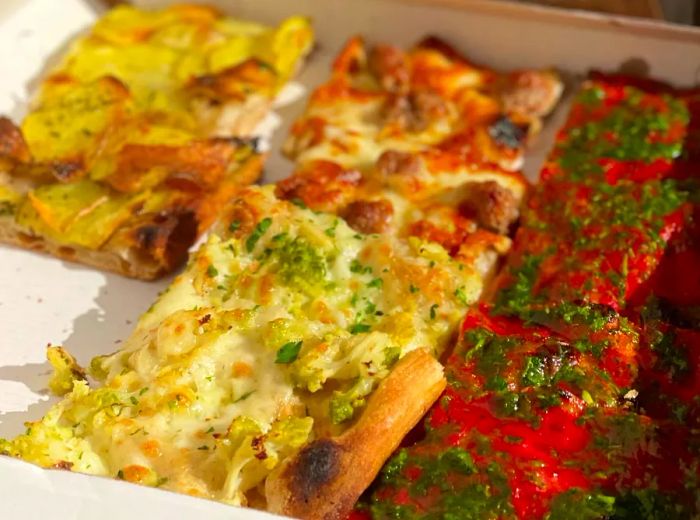 Slices of pizza topped with a variety of ingredients, neatly arranged in a takeout box.