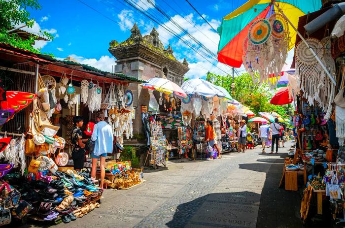 Numerous shoppers browse through souvenir stalls lining a street in Ubud, Bali.