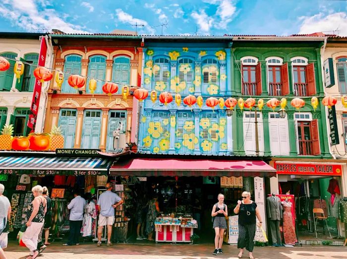 A bustling street scene in Singapore's Chinatown filled with tourists.