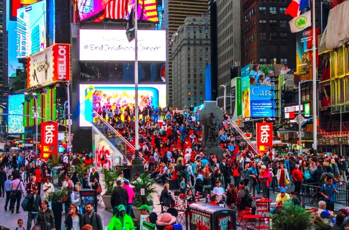 Crowds of people gather around the iconic red steps of the TKTS booth in Times Square