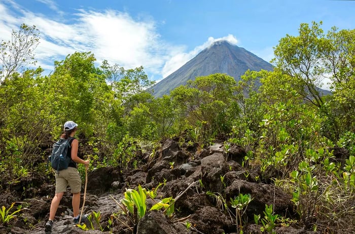 A woman hiking the Arenal 1968 Trail, Costa Rica, with the Arenal volcano in view.