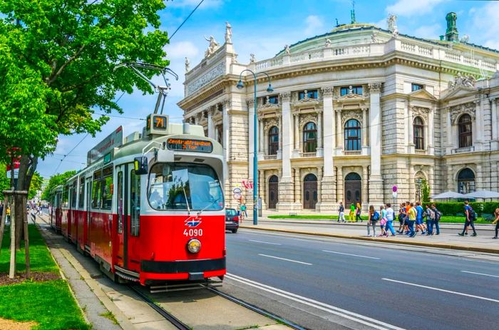 Visitors stroll along Vienna's Ringstrasse, passing the historic Burgtheater.