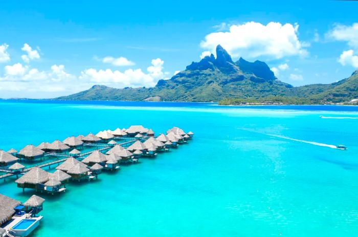 Aerial view of overwater bungalows above shimmering turquoise waters