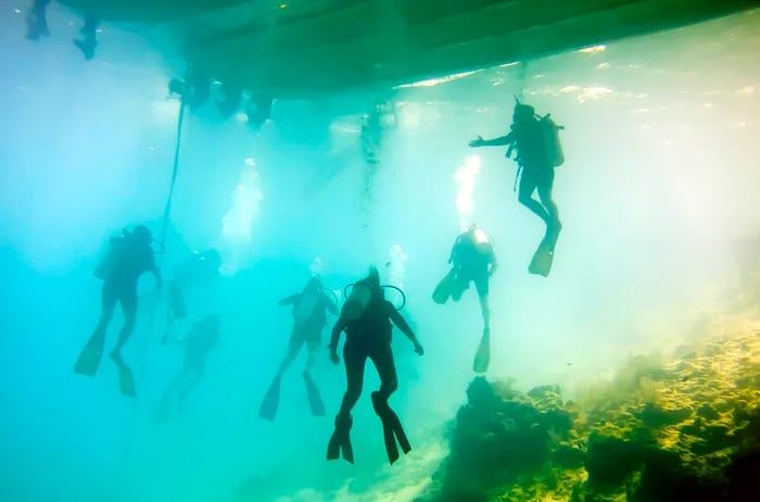 Diving enthusiasts explore the Blue Hole, a marine sinkhole at Lighthouse Reef in Belize.