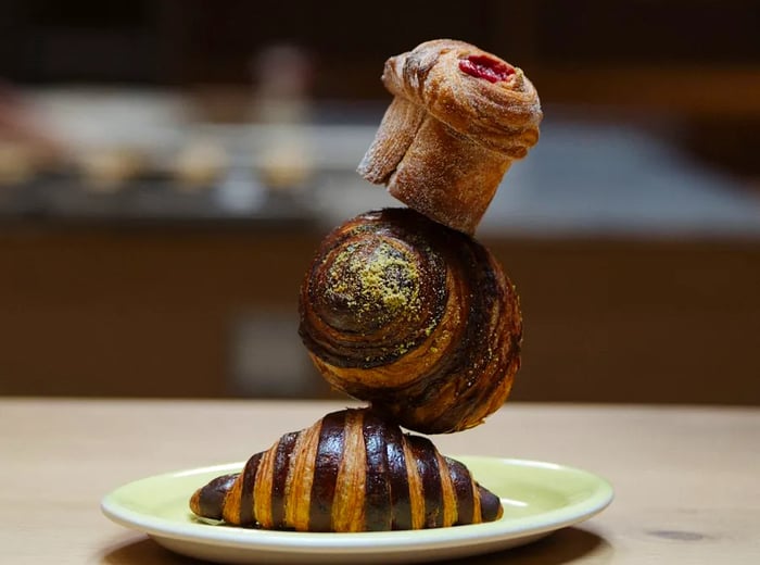 A muffin perched atop two flaky croissants.