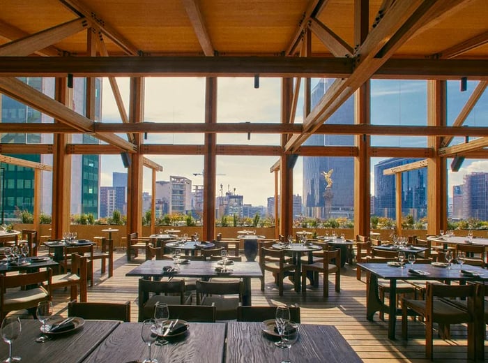 A panoramic view of the city skyline from a spacious dining area adorned with large windows.