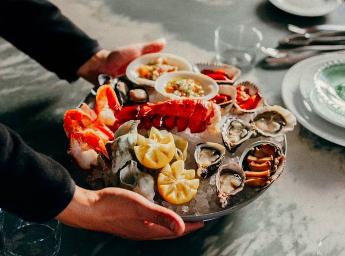 An ice-cold seafood platter featuring a large lobster tail, oysters, shrimp, and more.