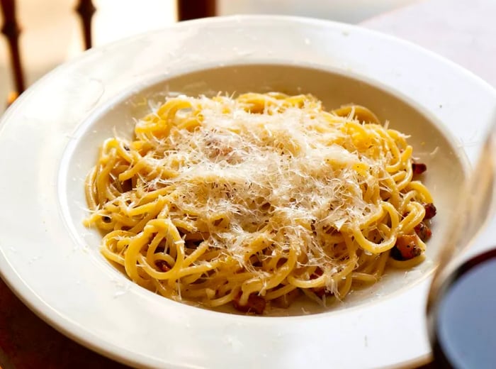 A dish of pasta generously sprinkled with grated cheese.