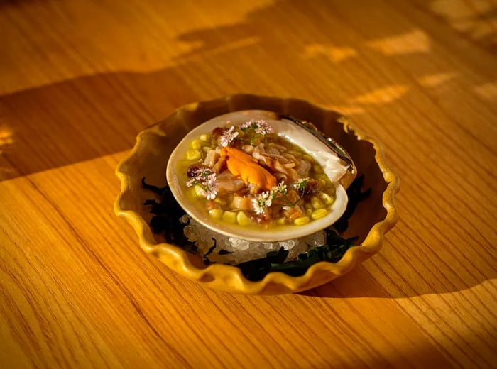 A large queen clam adorned with an array of toppings, elegantly presented in a decorative bowl.