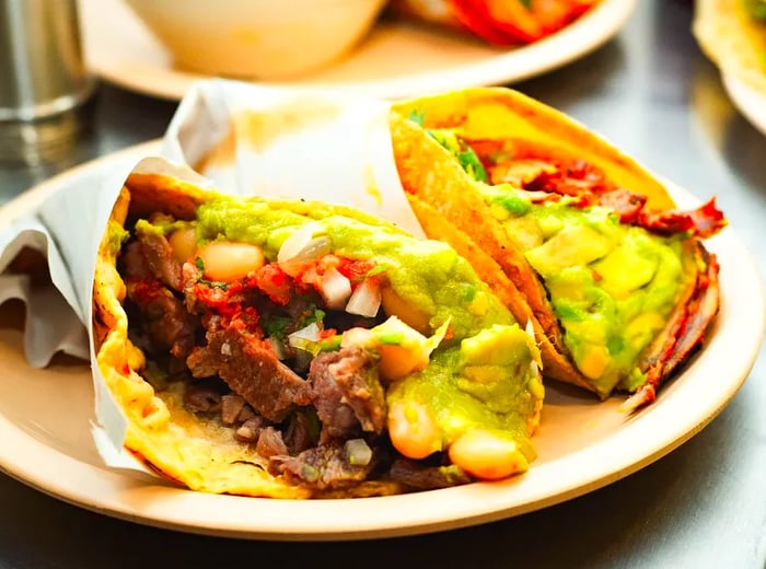 Two tacos brimming with meat and creamy guacamole.