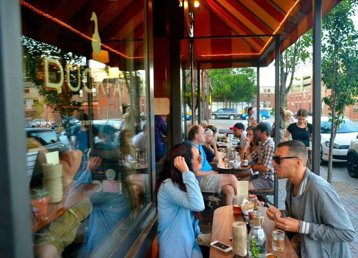 Diners enjoy meals at outdoor tables at Duckfat restaurant in Portland, Maine, USA