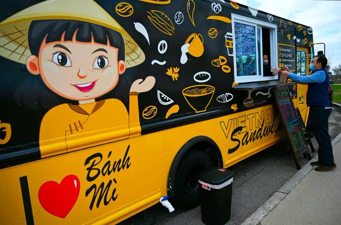 Phan serves a customer at the Vy Banh Mi food truck in Portland, Maine, USA