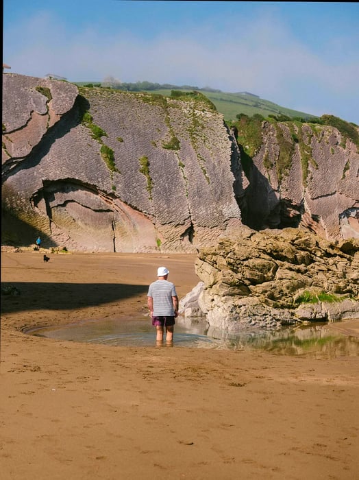 Tide pools within the eroded rock are filled with vibrant marine life.