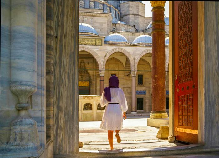 A young, beautiful Muslim woman poses in the courtyard of the Suleymaniye Mosque in Istanbul, Turkey.