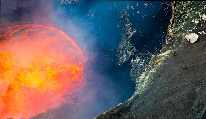 A fiery orange lake of lava with two hikers standing at the rim, gazing down into the depths