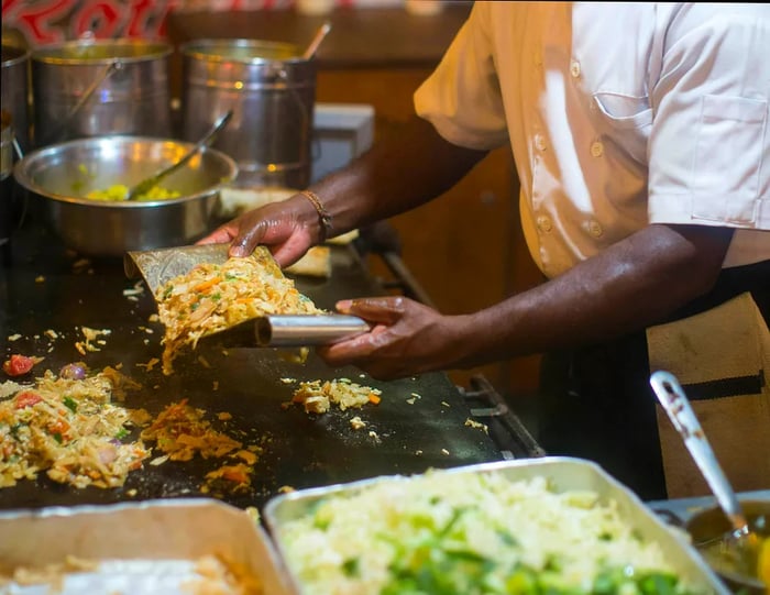 A close-up of a chef preparing street food on a griddle.