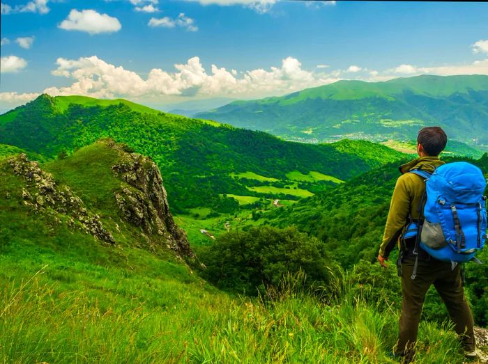 A hiker gazes over the lush hills and valley of Dilijan National Park, Armenia