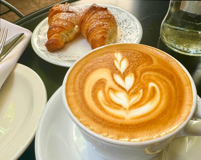 A close-up of cappuccino and a cornetto pastry