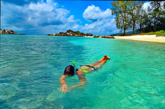 A woman snorkeling in a vibrant blue lagoon at Kecil Beach, Perhentian Islands