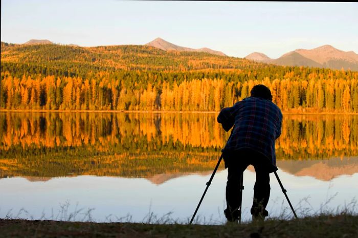 A man captures images of autumn foliage along the banks of Seeley Lake in Montana.