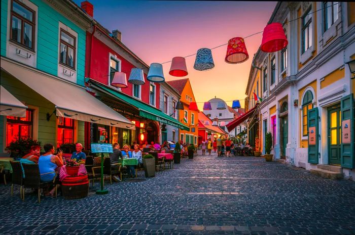 Diners enjoying their meals at restaurants and cafés in Szentendre’s old town during sunset.