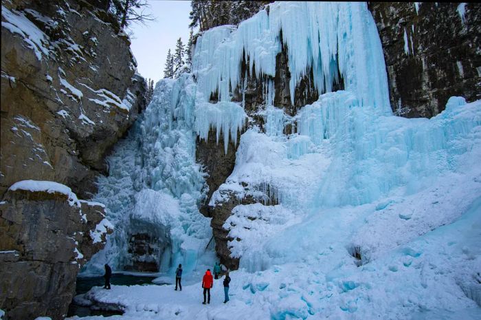 Hikers gather at the base of a frozen waterfall