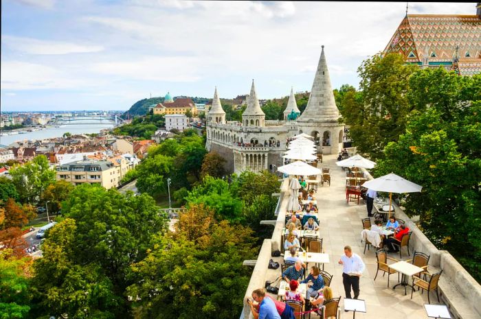 Diners enjoy meals outdoors at a restaurant beside Fisherman's Bastion.