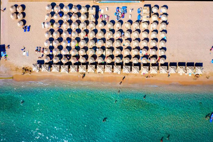 Aerial view of beachgoers enjoying Varkiza Beach with umbrellas and loungers