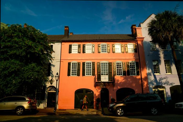 A man strolls past a pink house on Rainbow Row in Charleston, SC.