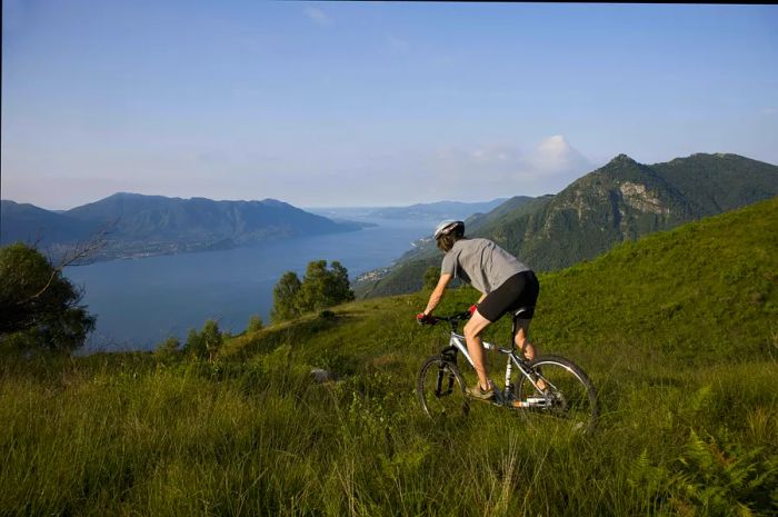 A young man rides a mountain bike by Lake Maggiore.