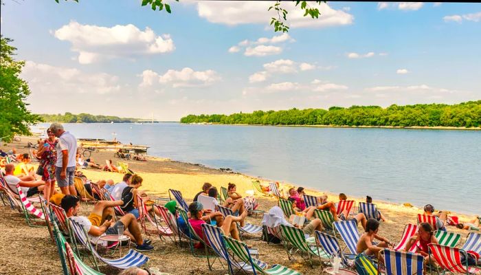 Visitors enjoy relaxing in deck chairs by the Danube River in Budapest.