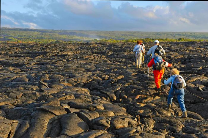 A group of hikers traverses a black lava terrain