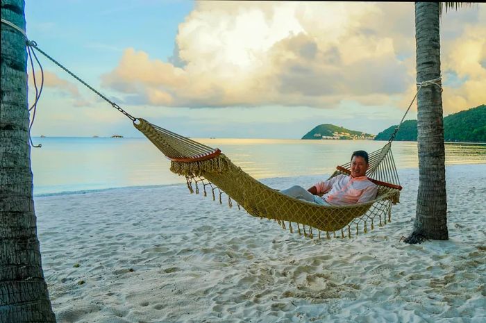 Dinogo Planet destination editor James Pham relaxes in a hammock nestled between two palm trees on Kem Beach, Phu Quoc, Vietnam.