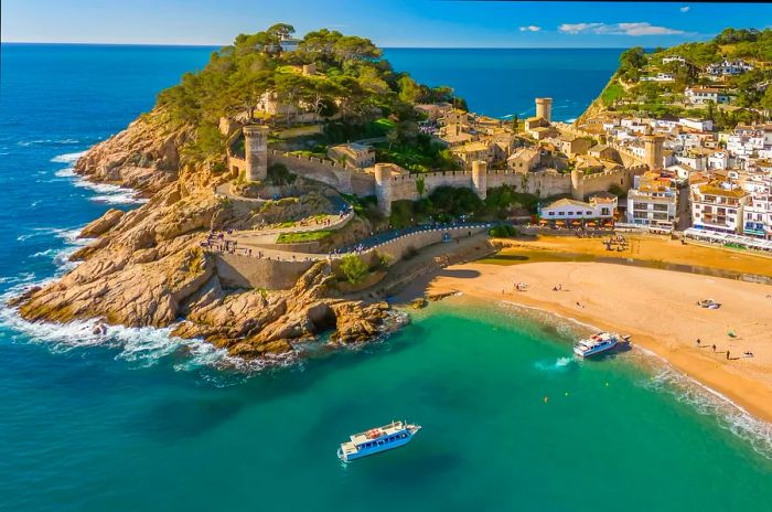 An aerial perspective of boats nearing the beach at Tossa de Mar, Costa Brava, Catalonia, Spain