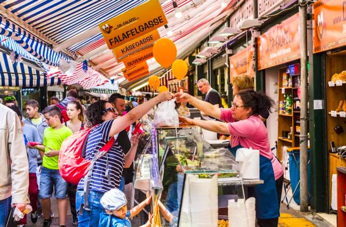 Shoppers browsing the food stalls at Naschmarkt in Vienna, Austria