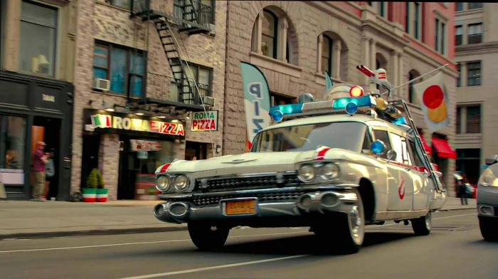 A vehicle resembling a police car, equipped with extra lights and mounted weapons, speeds through a city street.