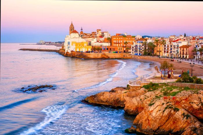 A breathtaking view of the beach and the historic town along the Mediterranean at sunrise, Sitges, Catalonia, Spain