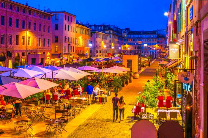 A nighttime view of a bustling square filled with restaurants in the old port area of Marseille, France