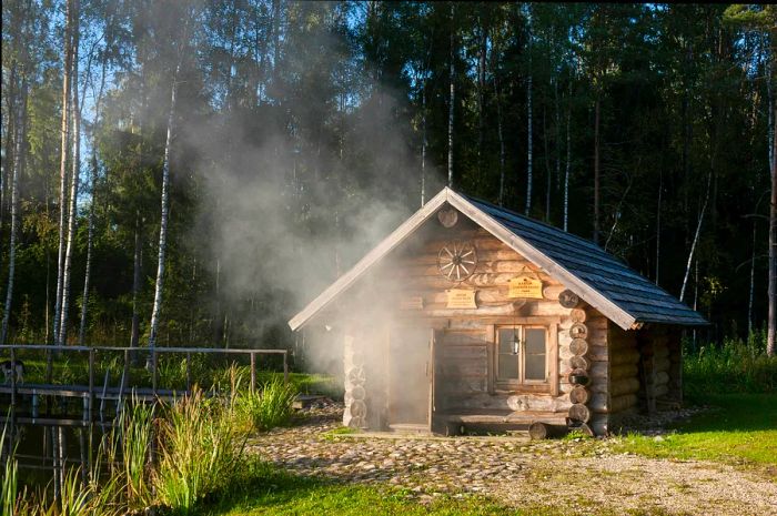 A quaint wooden cabin exudes smoke and steam from its open door.